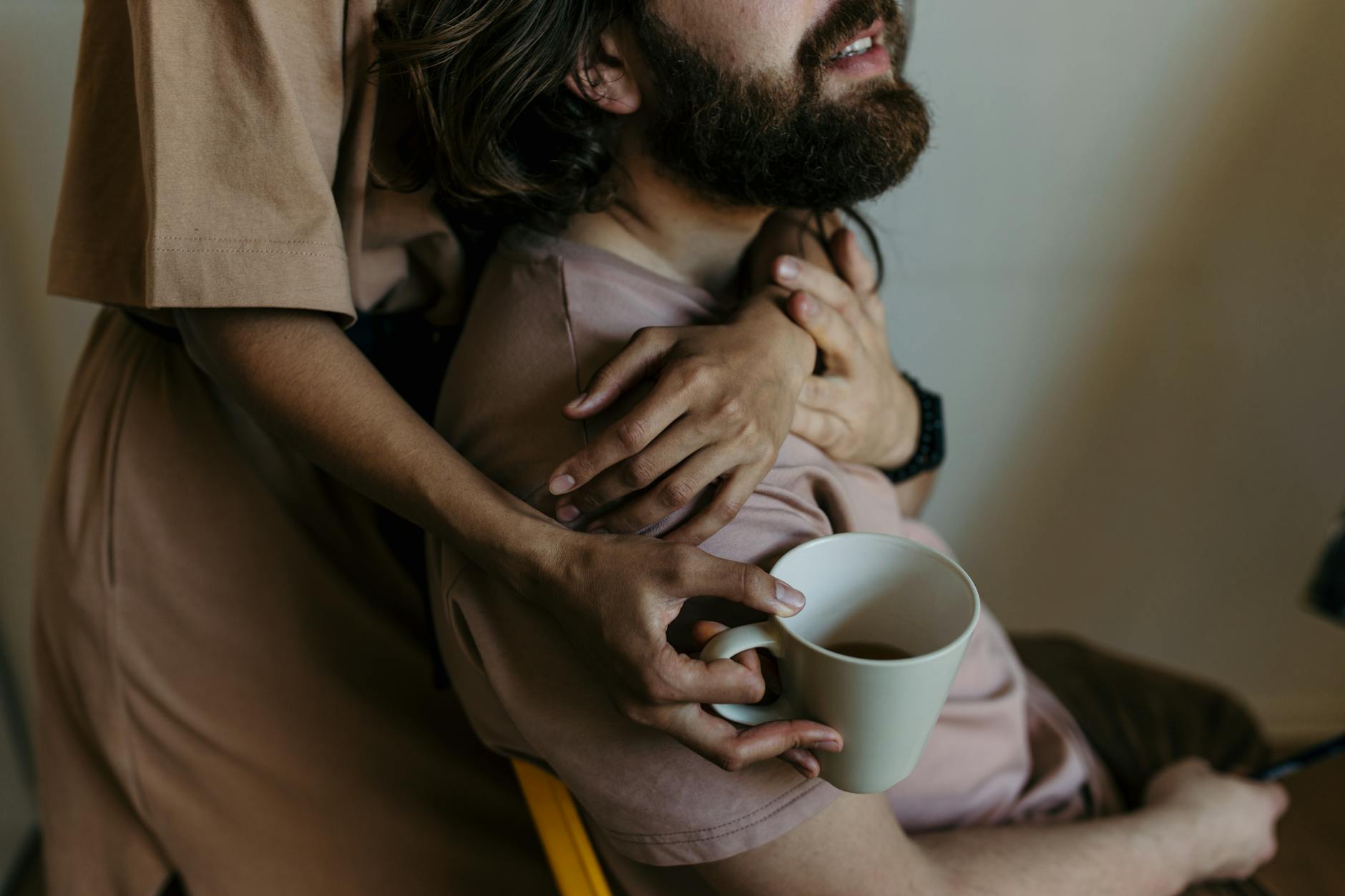 A couple in a warm embrace enjoying coffee, embodying a relaxed and loving atmosphere.
