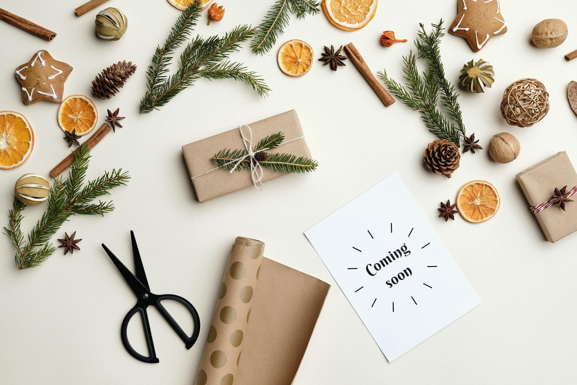 A top-down view of holiday decorations including wrapped gifts, pine sprigs, and dried oranges.
