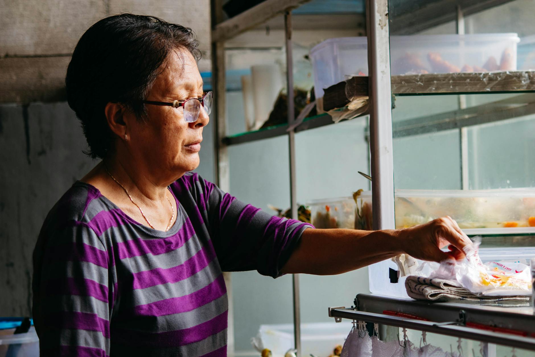 Woman in striped shirt preparing food in an indoor kitchen setting.